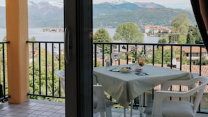 Un balcón con una mesa dispuesta para dos, con vistas a un lago y montañas.
