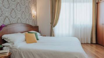 Un letto rifatto con cuscini bianchi e verdi, una testiera in legno e uno sfondo decorato.