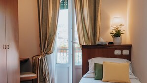 Habitación de hotel con cama, una silla, un escritorio, una lámpara y vista al exterior.
