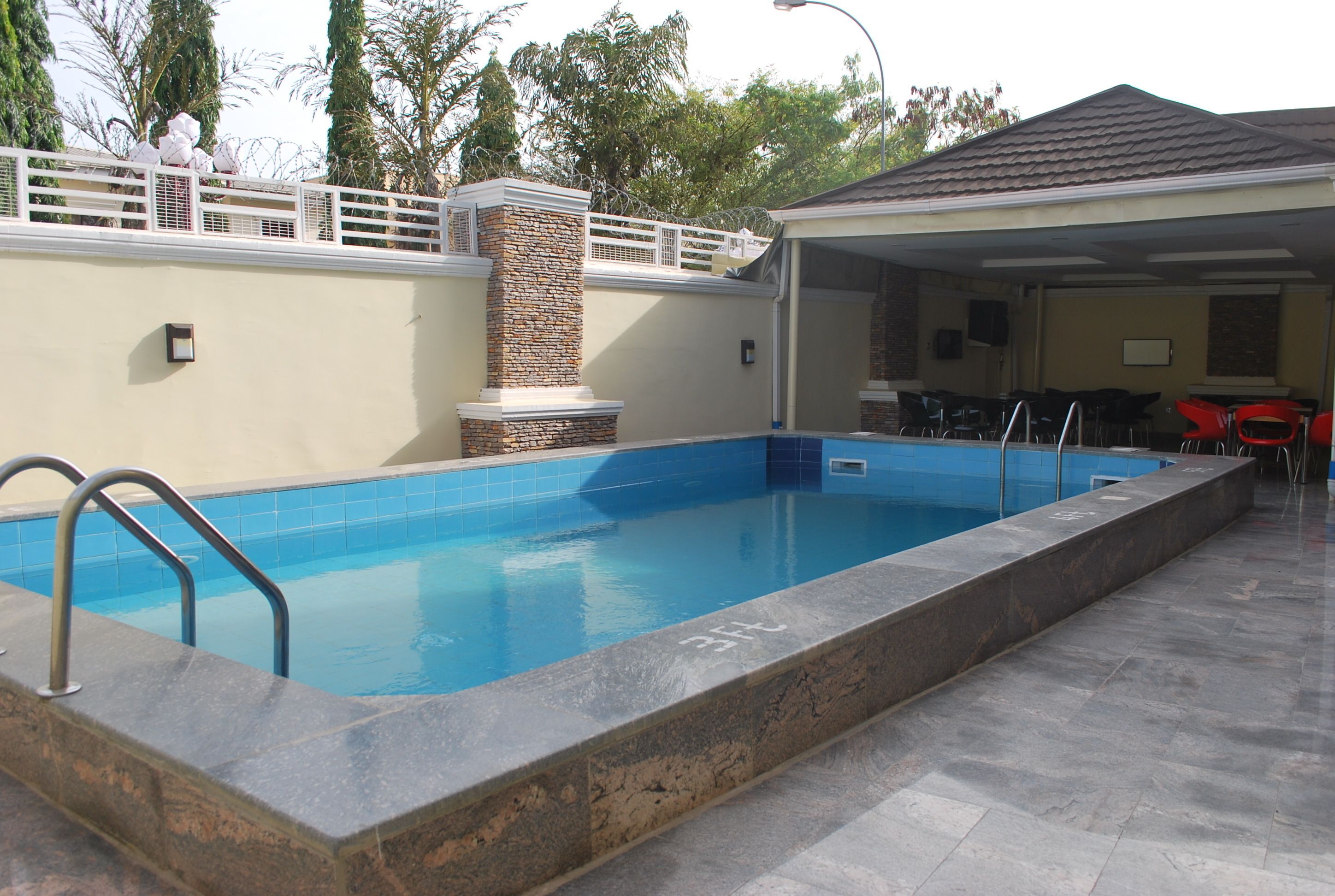 A rectangular swimming pool with a stone border and a metal ladder.