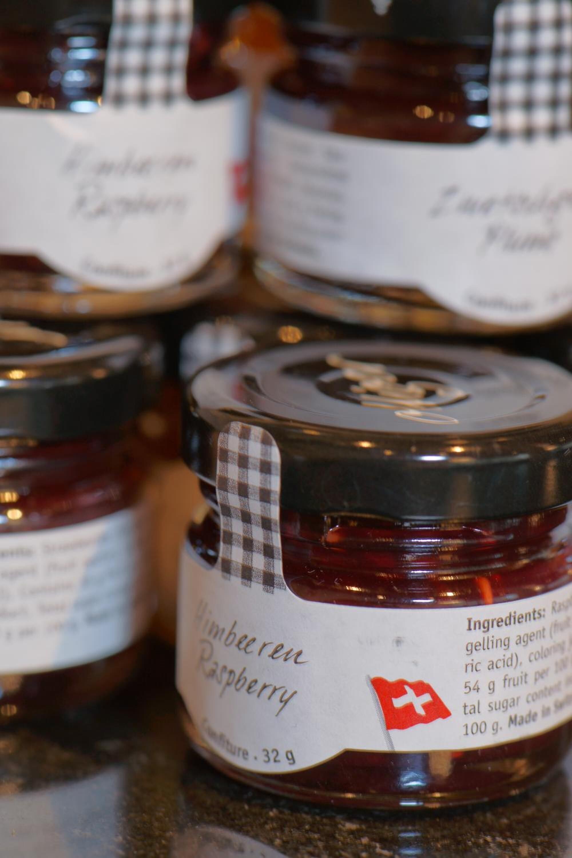 A close-up of several jars of raspberry jam with labels.