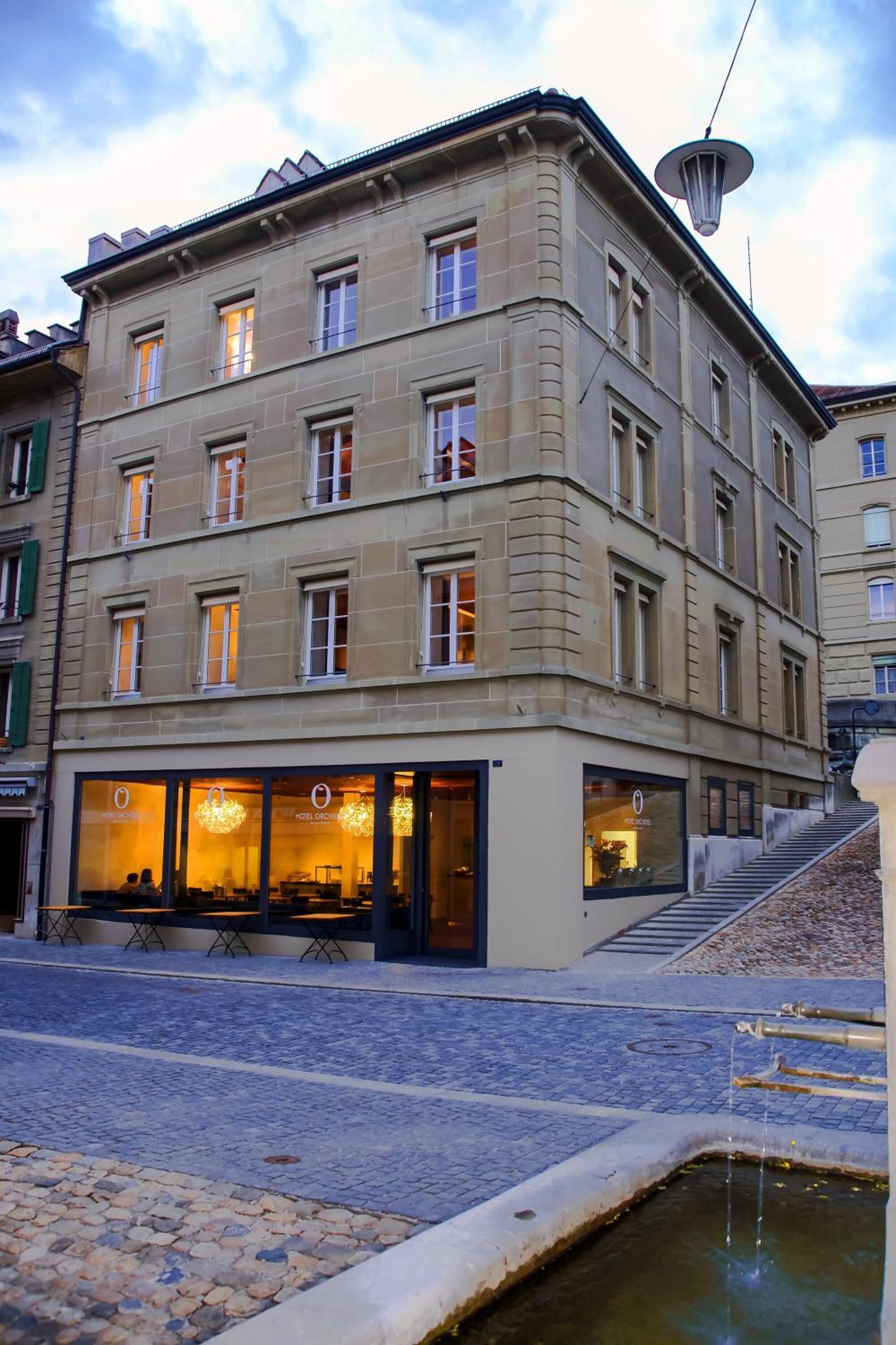 A multi-story hotel with a stone facade, large windows, and outdoor seating.