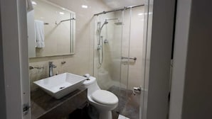 A modern bathroom with a glass shower enclosure, a white sink, and a toilet. - Hotel Veler (Medellín)