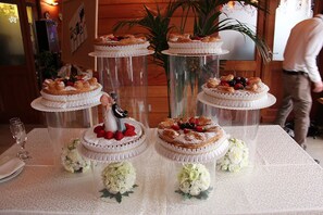 A table with tiered cake stands, each topped with a cake and surrounded by white flowers.