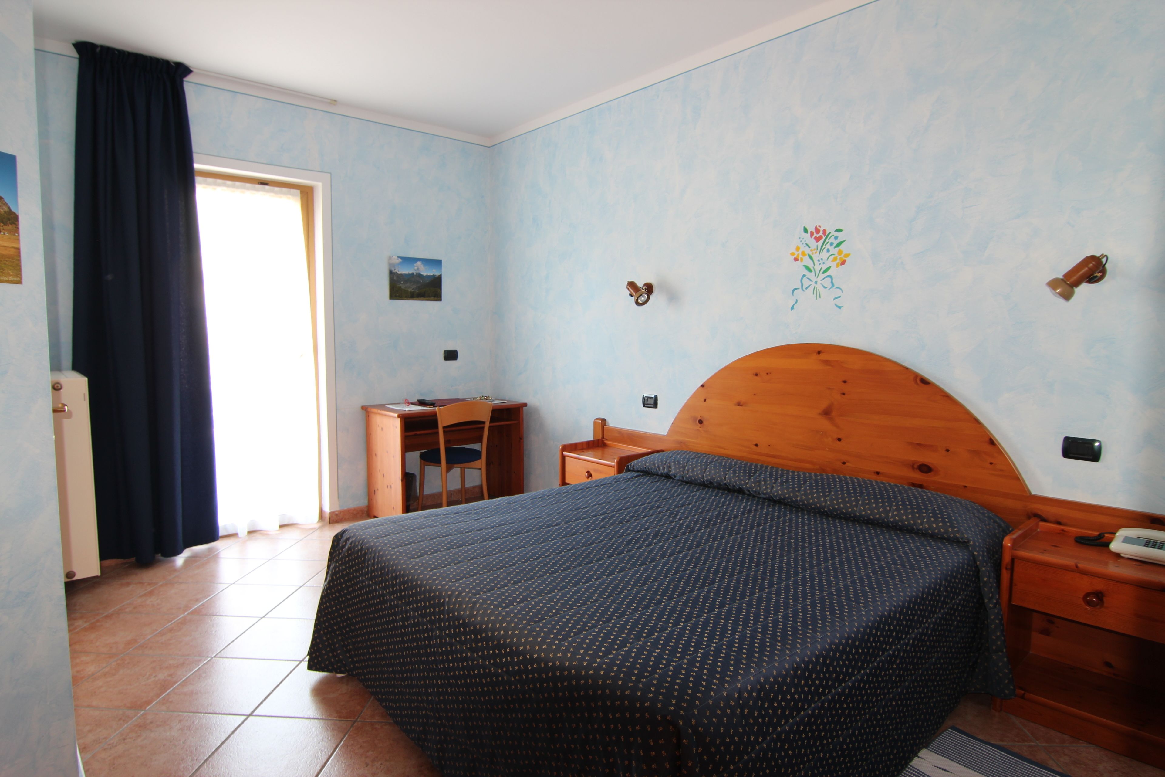 Un dormitorio con cama, cabecera de madera, un escritorio y una silla.
