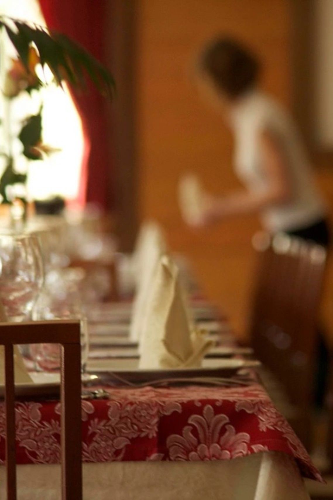 Una mesa de comedor con mantel rojo y blanco, un jarrón con flores y una silla.