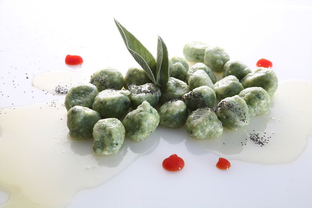Un postre con bolitas verdes y una ramita de romero sobre un plato blanco.