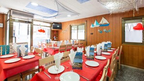 A dining area with red tablecloths, wooden chairs, and nautical-themed decor. - Pensión Galicia (Canovelles)
