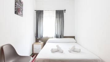 Une chambre d’hôtel avec un lit, une chaise, une table de chevet et une fenêtre avec des rideaux.