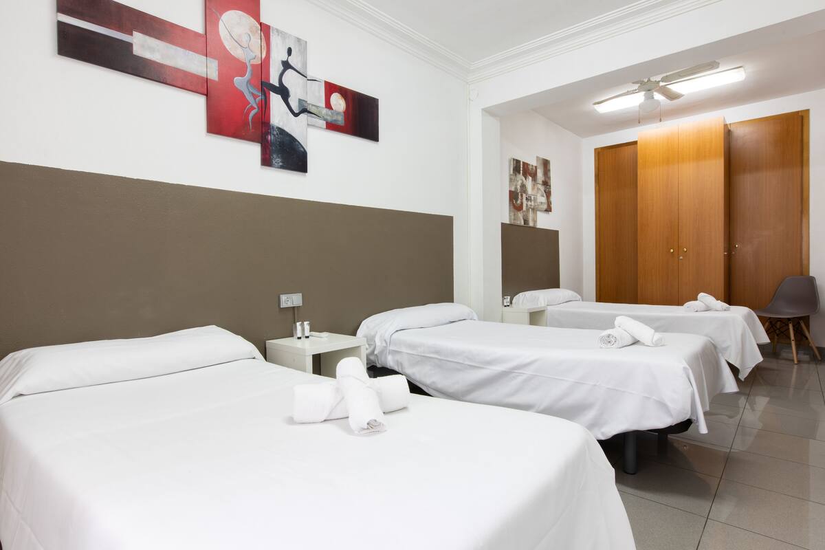 Een hotelkamer met twee enkele bedden, een houten garderobe, een bureau met stoel, en kunst aan de muur.
