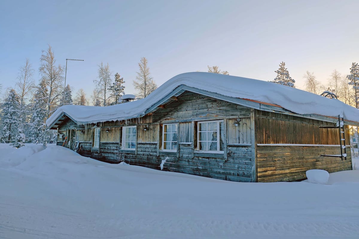 A rustic wooden cabin surrounded by snow-covered trees.
