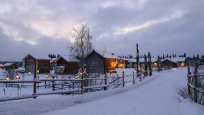 Un pueblo cubierto de nieve con cabañas de madera y una valla de madera.