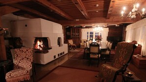 Una sala de estar acogedora con chimenea, vigas de madera en el techo y un comedor con candelabro.