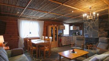 Interior acolhedor de uma cabana, com sala de jantar, sala de estar e cozinha.