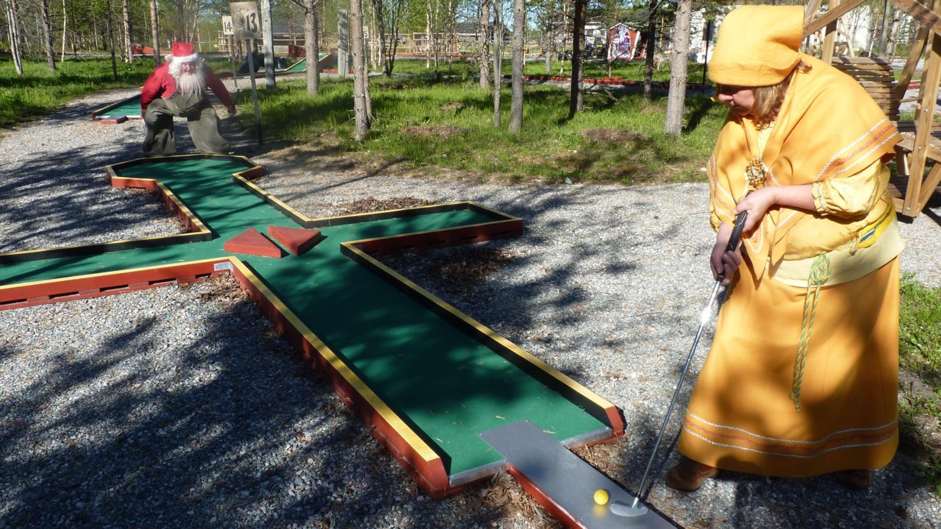 Un parcours de minigolf avec des trous numérotés et une personne qui joue.