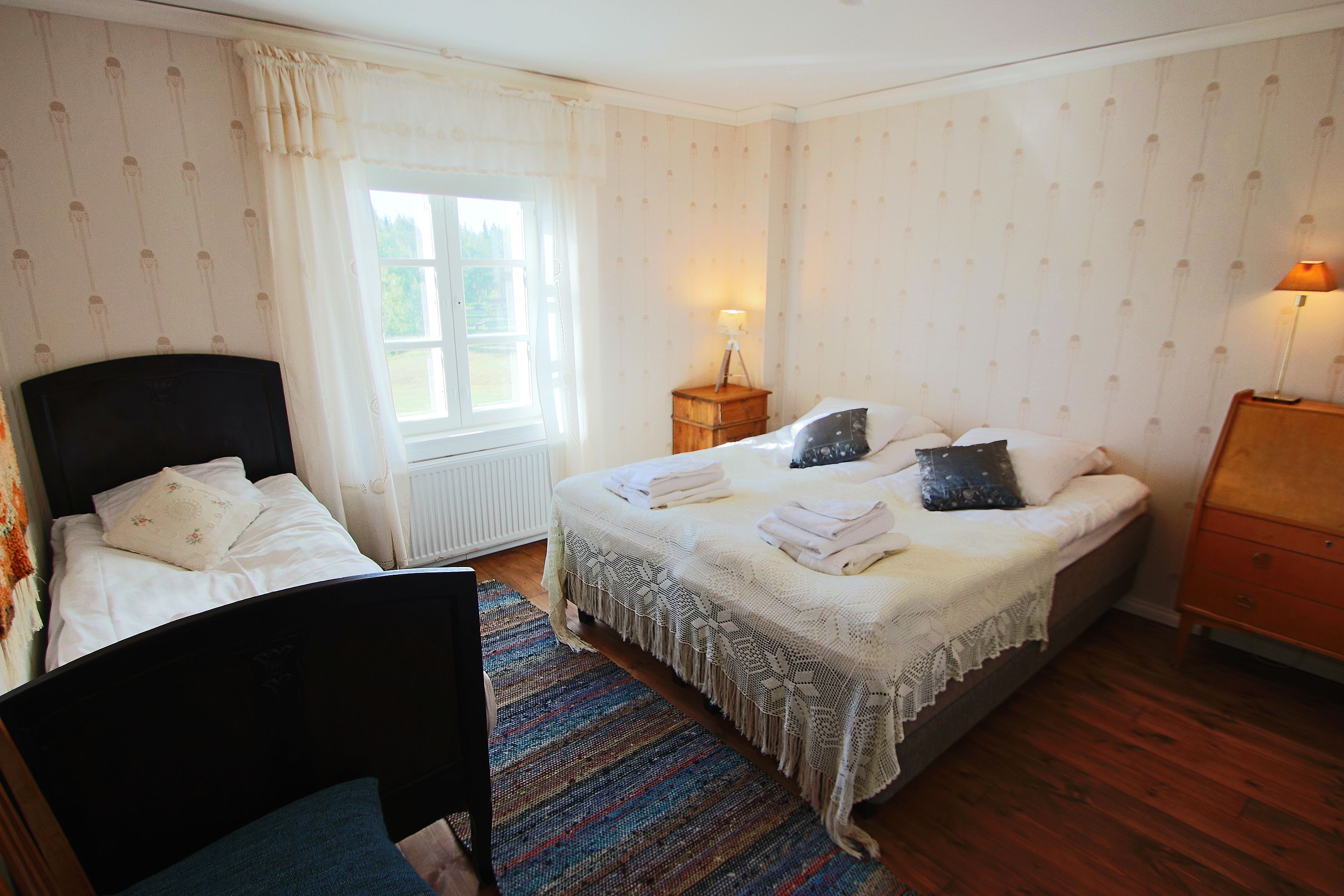 Ein Schlafzimmer mit Bett, Sessel, Schminktisch und Lampe.