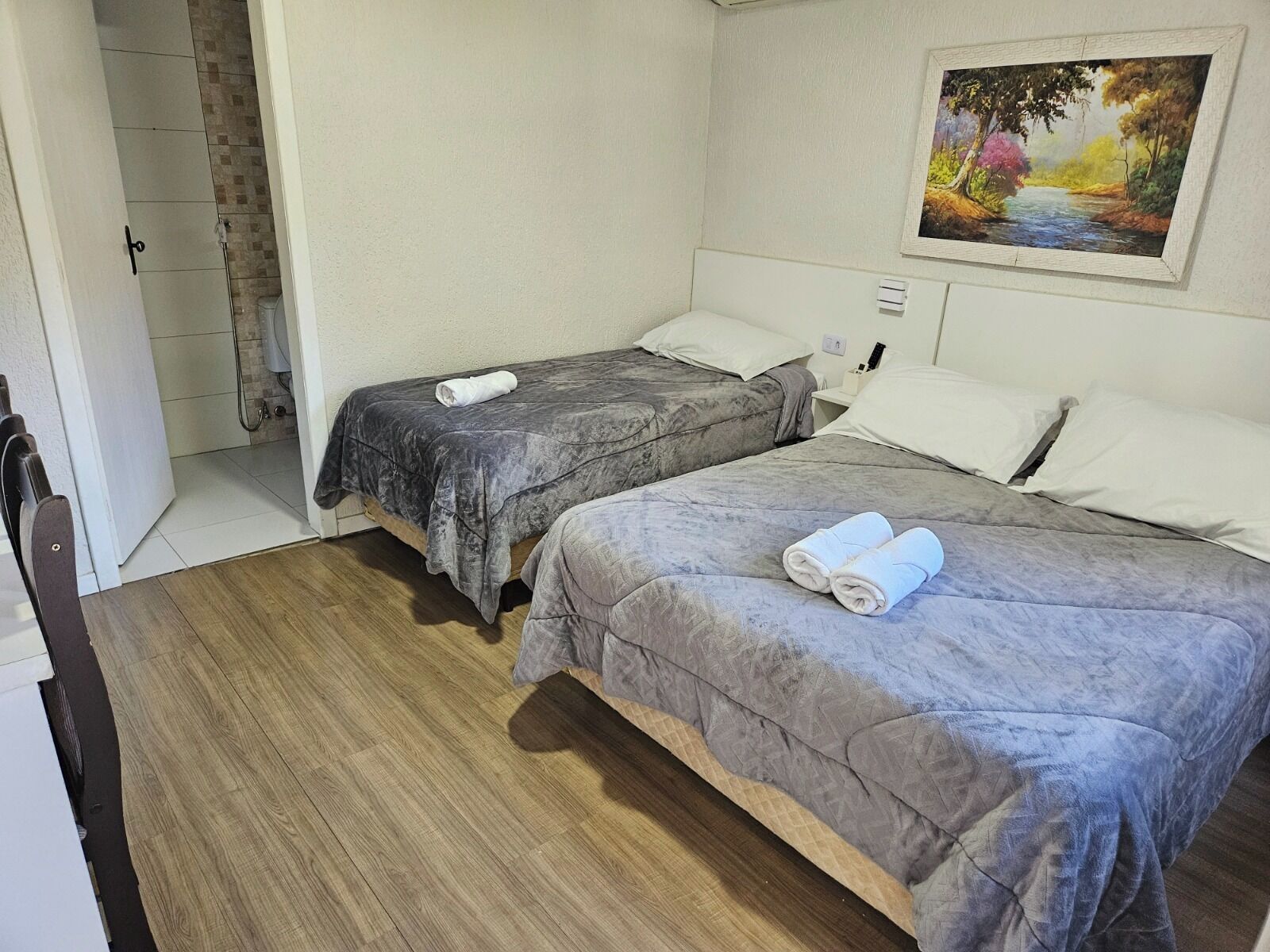 Une chambre avec deux lits, un tableau au mur et un espace douche.