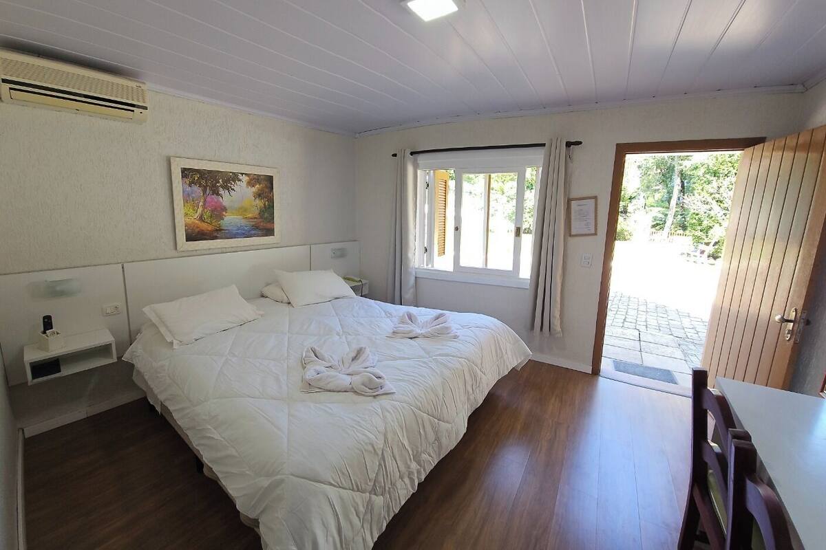 Un dormitorio con cama, un cuadro, una ventana y una puerta que da al exterior.