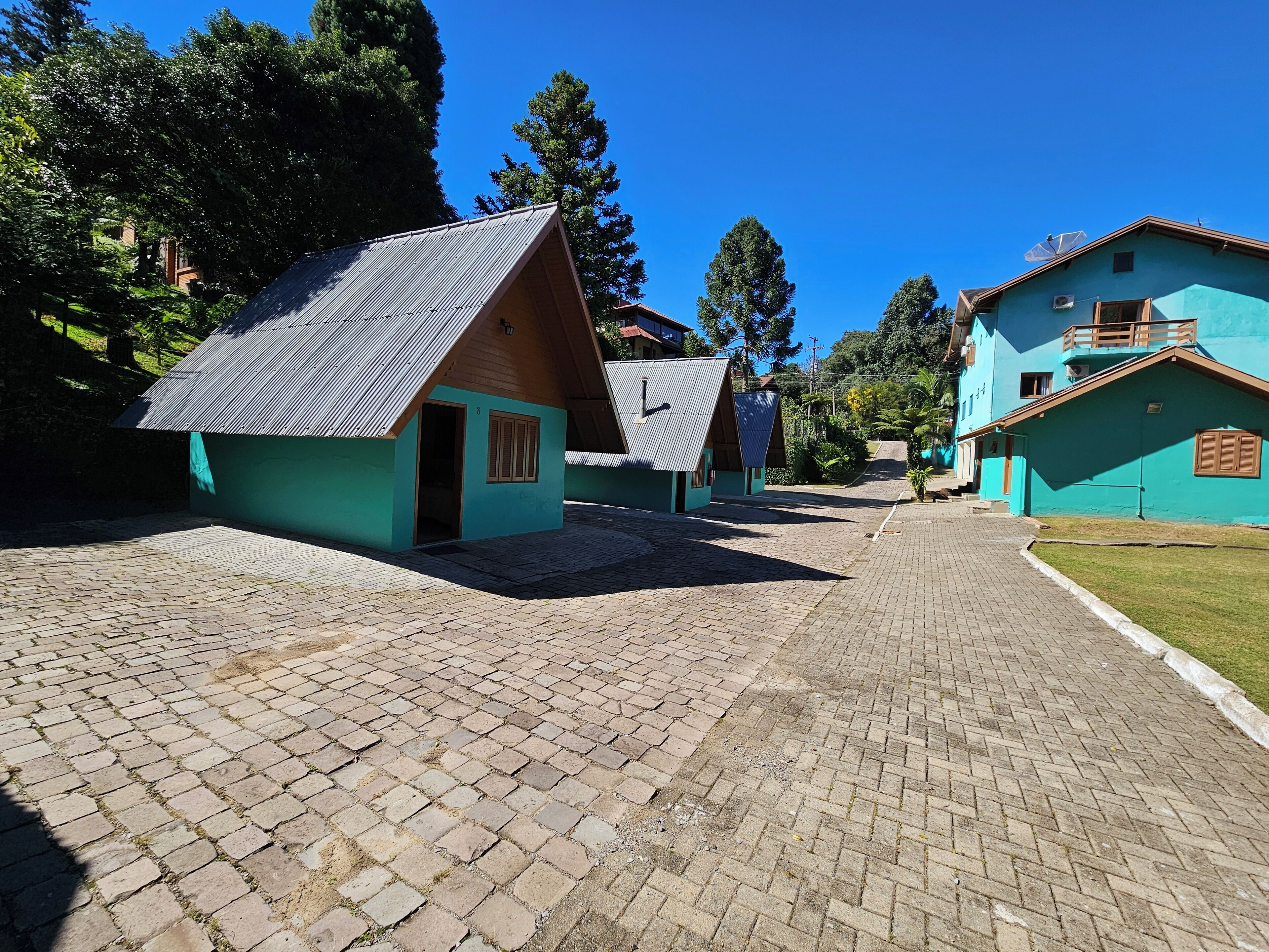 Un patio con edificios pequeños, senderos empedrados y vegetación circundante.