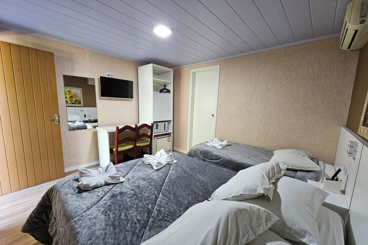Habitación de hotel con dos camas, un escritorio, una silla, un televisor y un aire acondicionado.