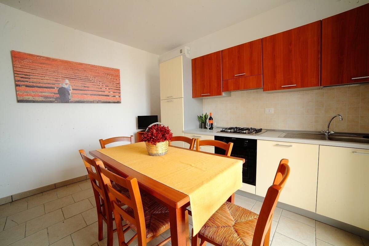 Una cocina compacta con armarios de madera, una mesa de comedor con sillas, una estufa y un lavamanos.