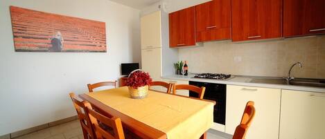 Una cocina compacta con armarios de madera, una mesa de comedor con sillas, una estufa y un lavamanos.