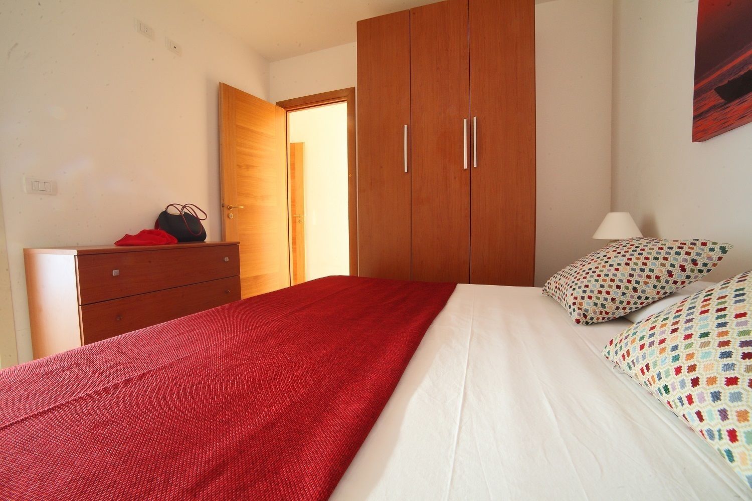 Une chambre à coucher avec un lit, une armoire en bois, une commode et une lampe.