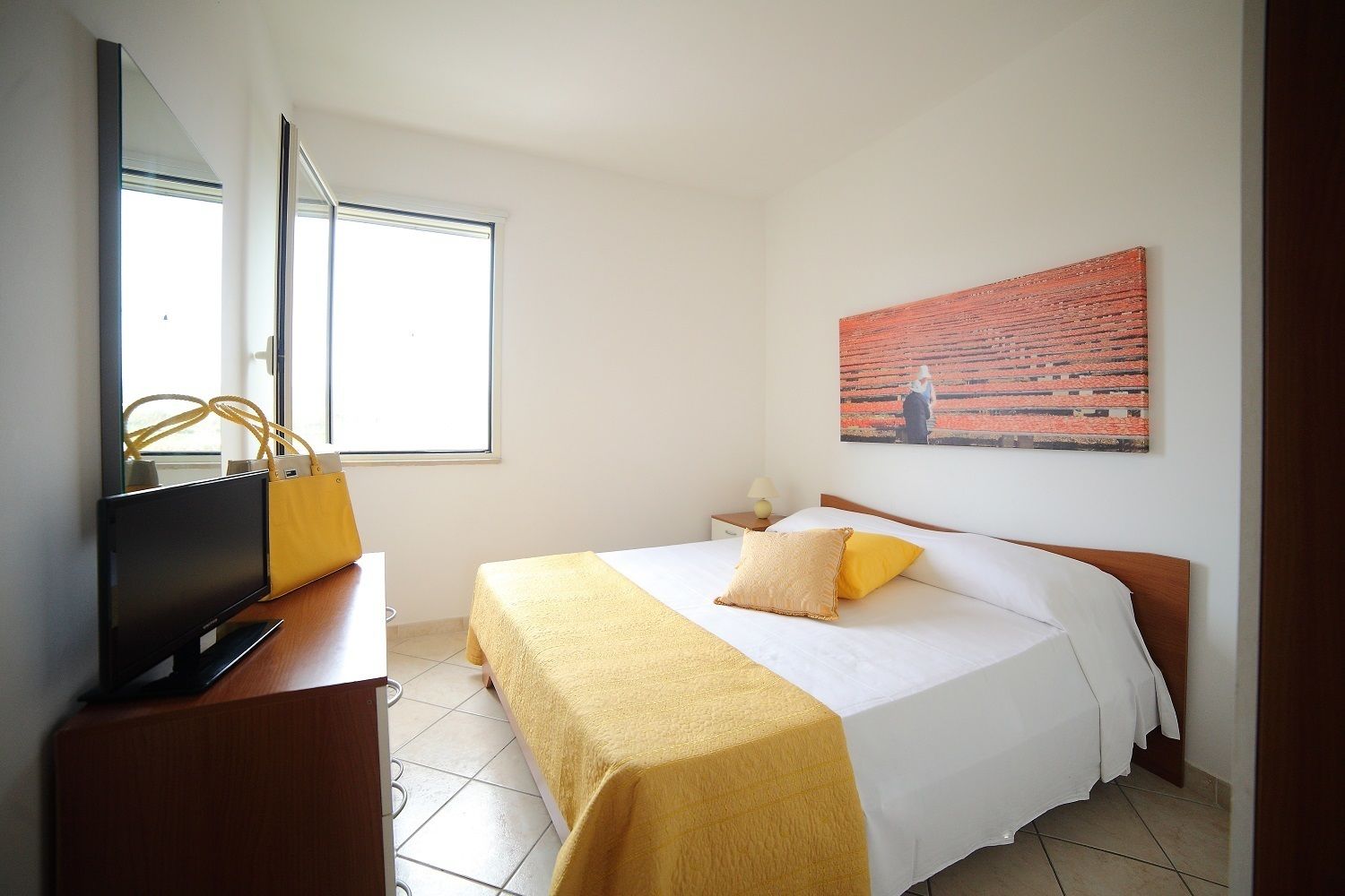 Une chambre d’hôtel avec un lit, une télévision, une fenêtre et un tableau au mur.