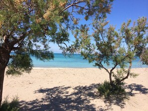 A beach with clear blue water and sandy shore, surrounded by trees. - Residence Riva Mare Ugento (Ugento)