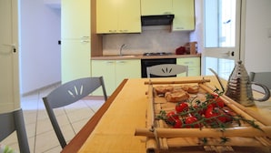 Une cuisine avec des meubles de couleur jaune, une table en bois et une fenêtre.