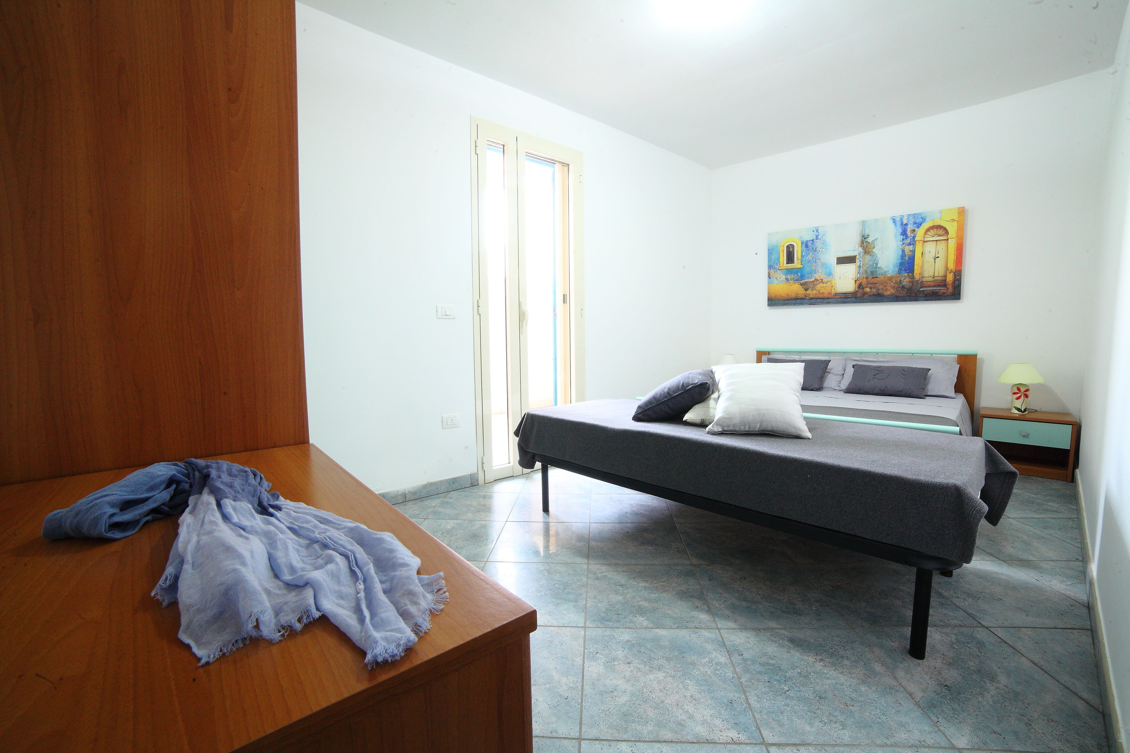 Un dormitorio con una cama, un aparador de madera y un cuadro en la pared.