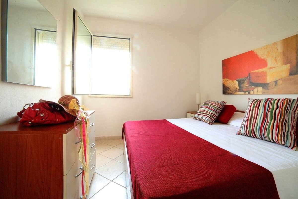 Una habitación de hotel con cama, cómoda, espejo y ventana.