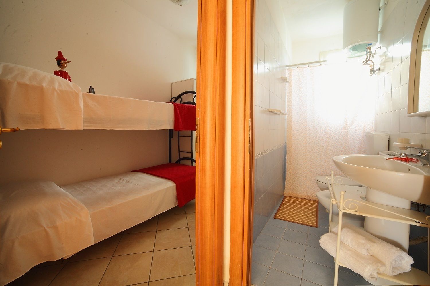 A small, compact room with a bunk bed, a shower area, and a sink.