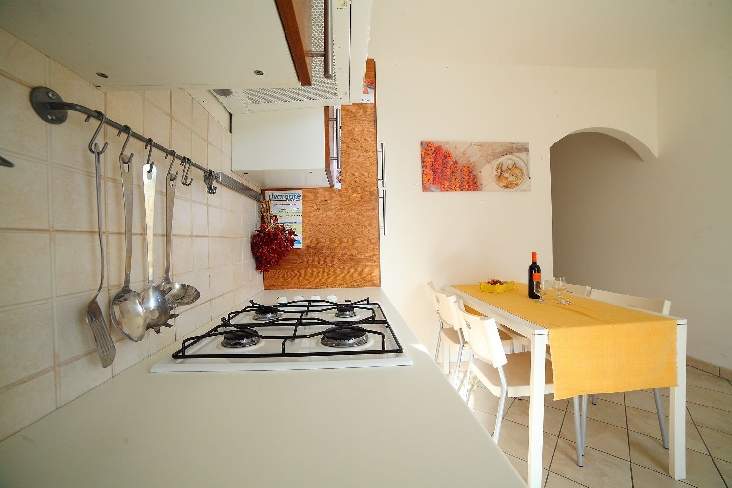 Cozinha com fogão a gás, utensílios pendurados e mesa de jantar com cadeiras.