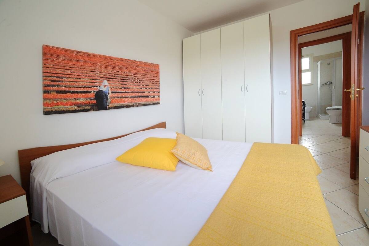 Un dormitorio con cama, un armario blanco y un cuadro en la pared.
