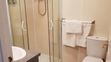 Un baño con ducha de vidrio, inodoro blanco y lavamanos.