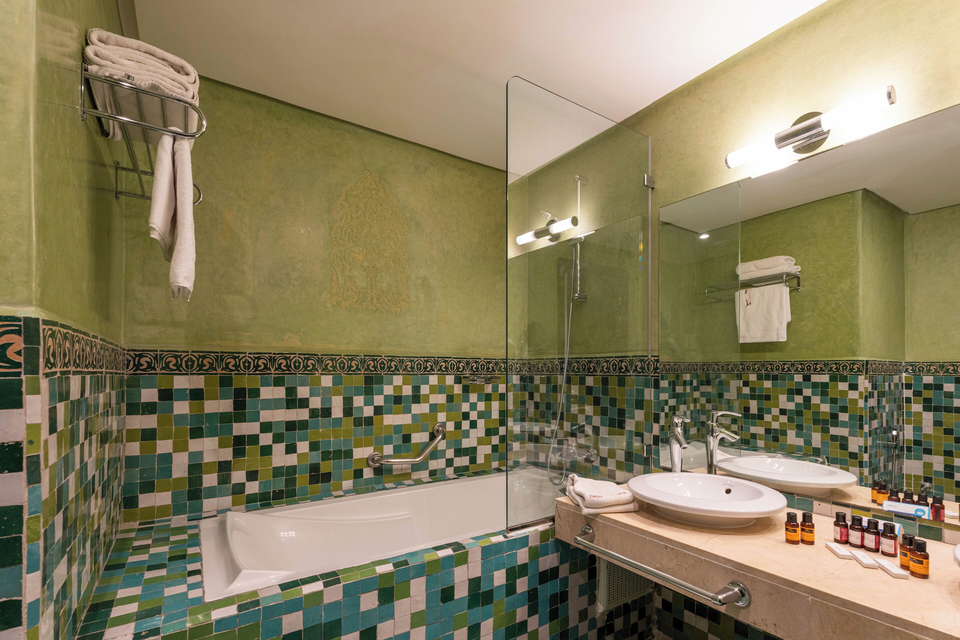 A bathroom with a bathtub, two sinks, a glass shower enclosure, and a tiled backsplash.