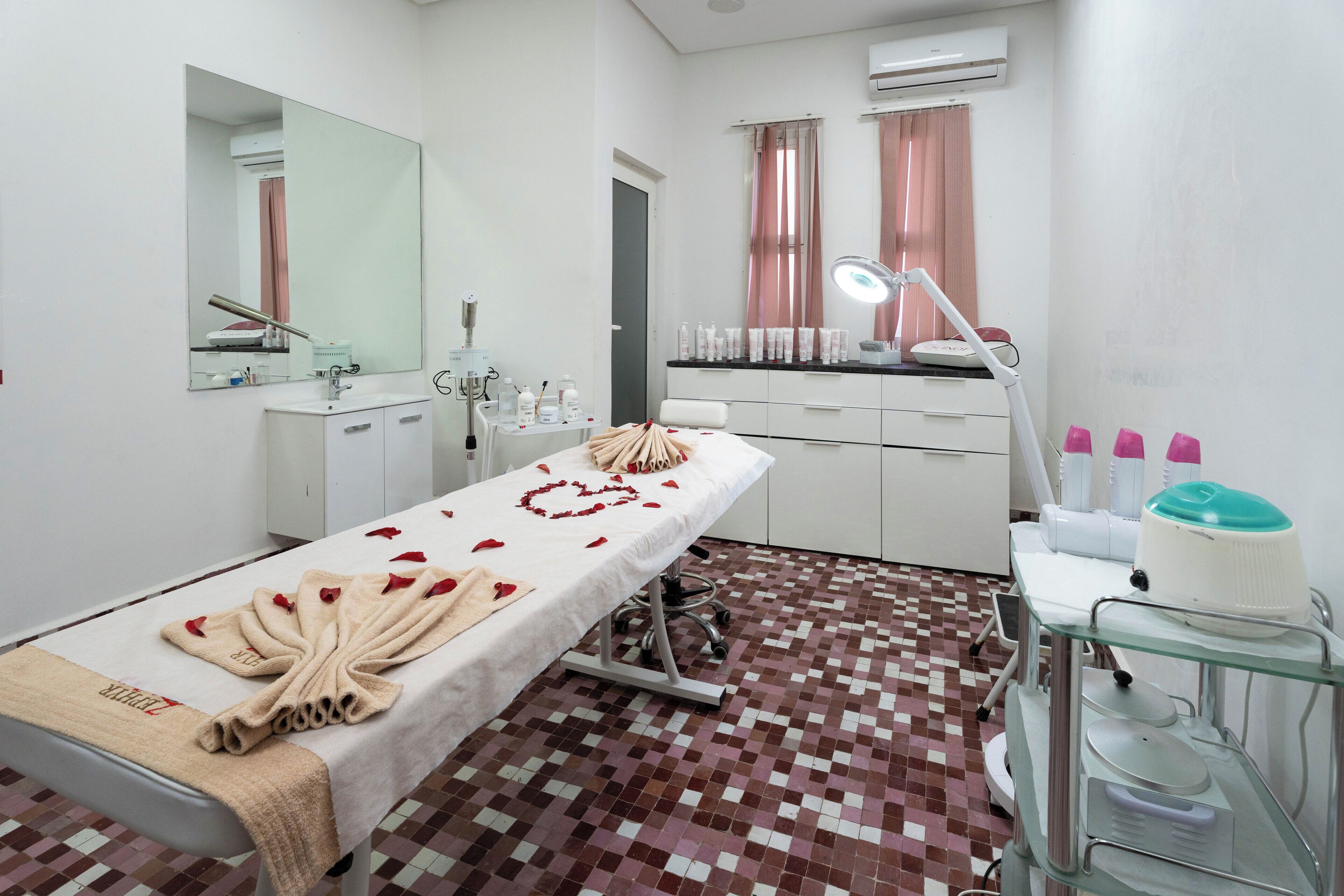 Una habitación limpia y bien iluminada con una cama, un espejo, tocador con lavabo y un armario de vidrio con artículos de aseo.