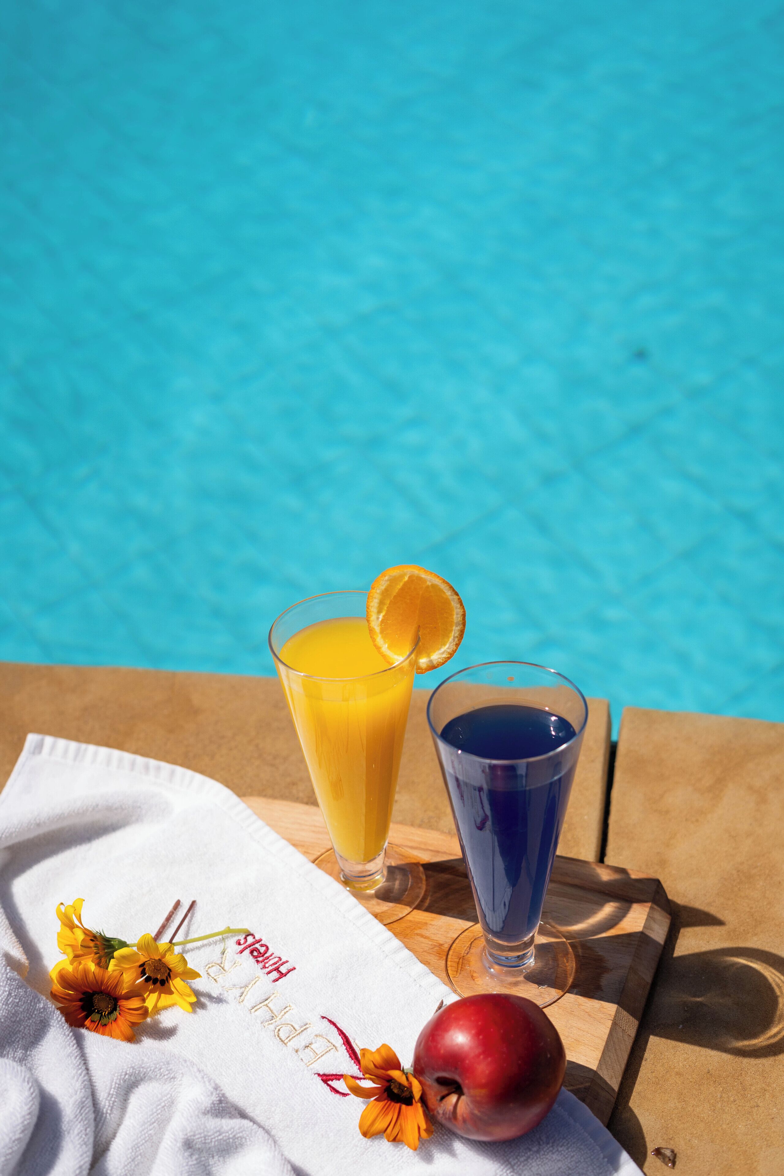 Une table avec des boissons et une serviette près d’une piscine.