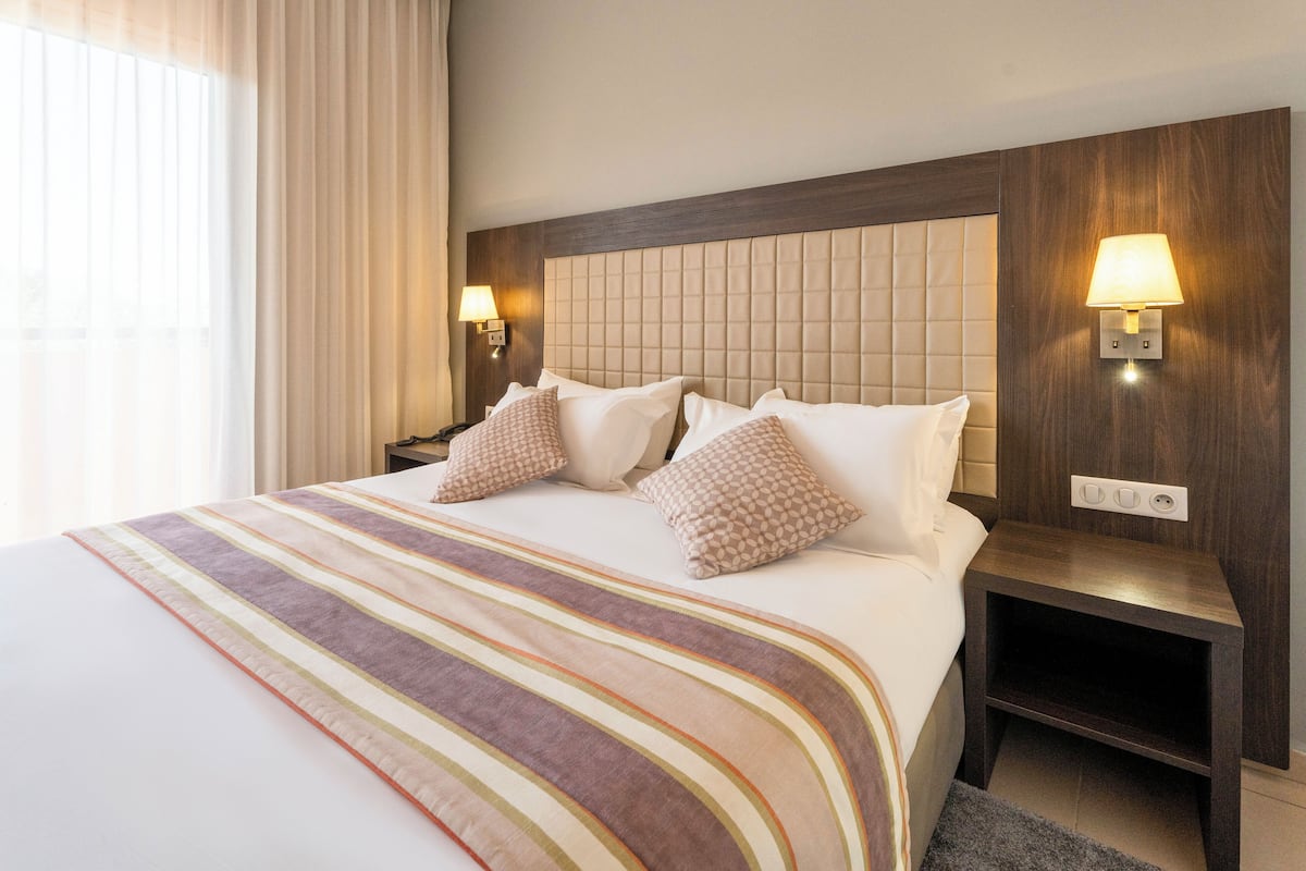 A hotel room with a large bed, two bedside tables, and a headboard with a light fixture.