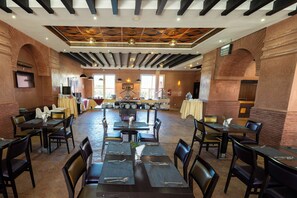 A spacious dining area with multiple tables and chairs, a central stage, and brick walls. - Zephyr Hotel Club Resort and Spa (Marrakech)