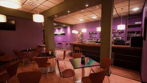 A restaurant with tables and chairs, a bar area, and purple walls.