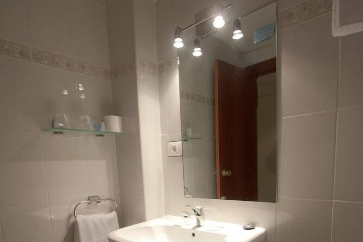 A bathroom with a white sink, mirror, and tiled walls.