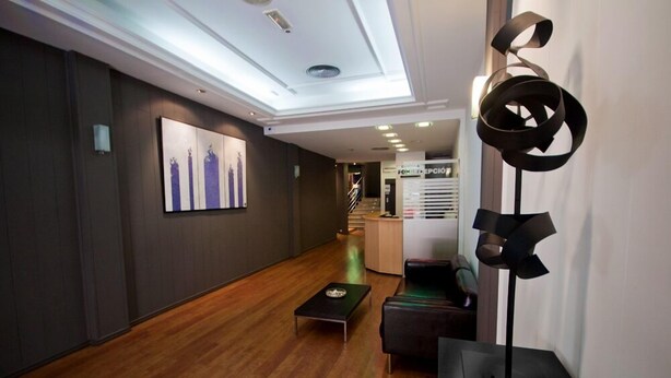 A modern lobby with a wooden floor, a black coffee table, a black sofa, and a unique abstract sculpture.