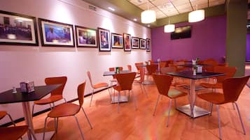 Un salón de conferencias con mesas y sillas, cuadros en la pared y una televisión.