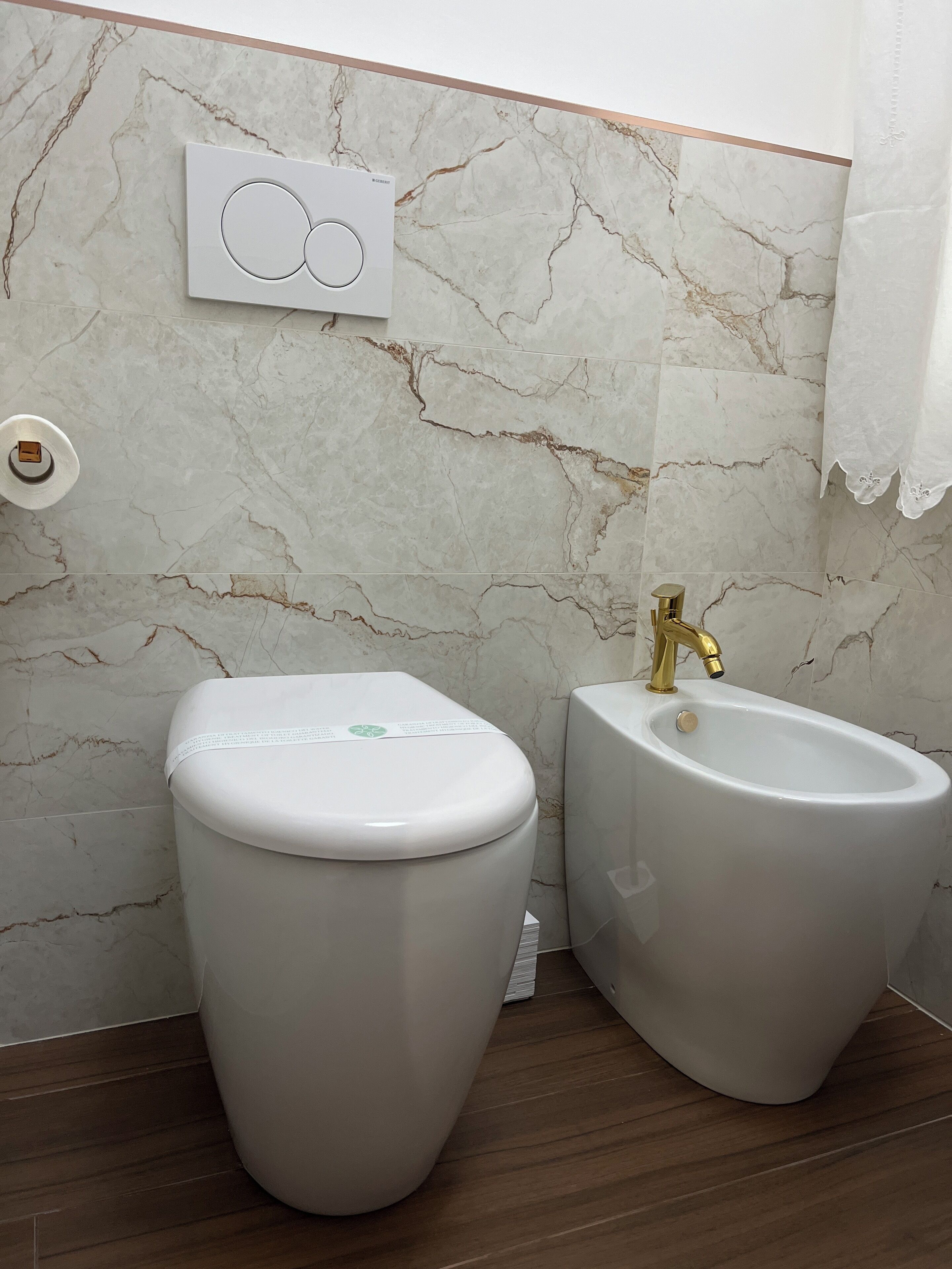 Een badkamer met toilet, bidet en marmeren wanden.