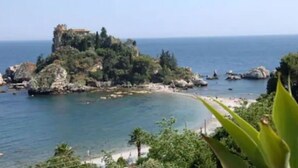 Un paisaje costero con una isla rocosa y una playa.