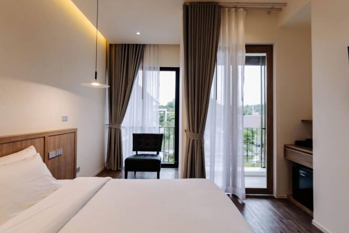A hotel room with a bed, a chair, a desk, and a view of the outdoors.