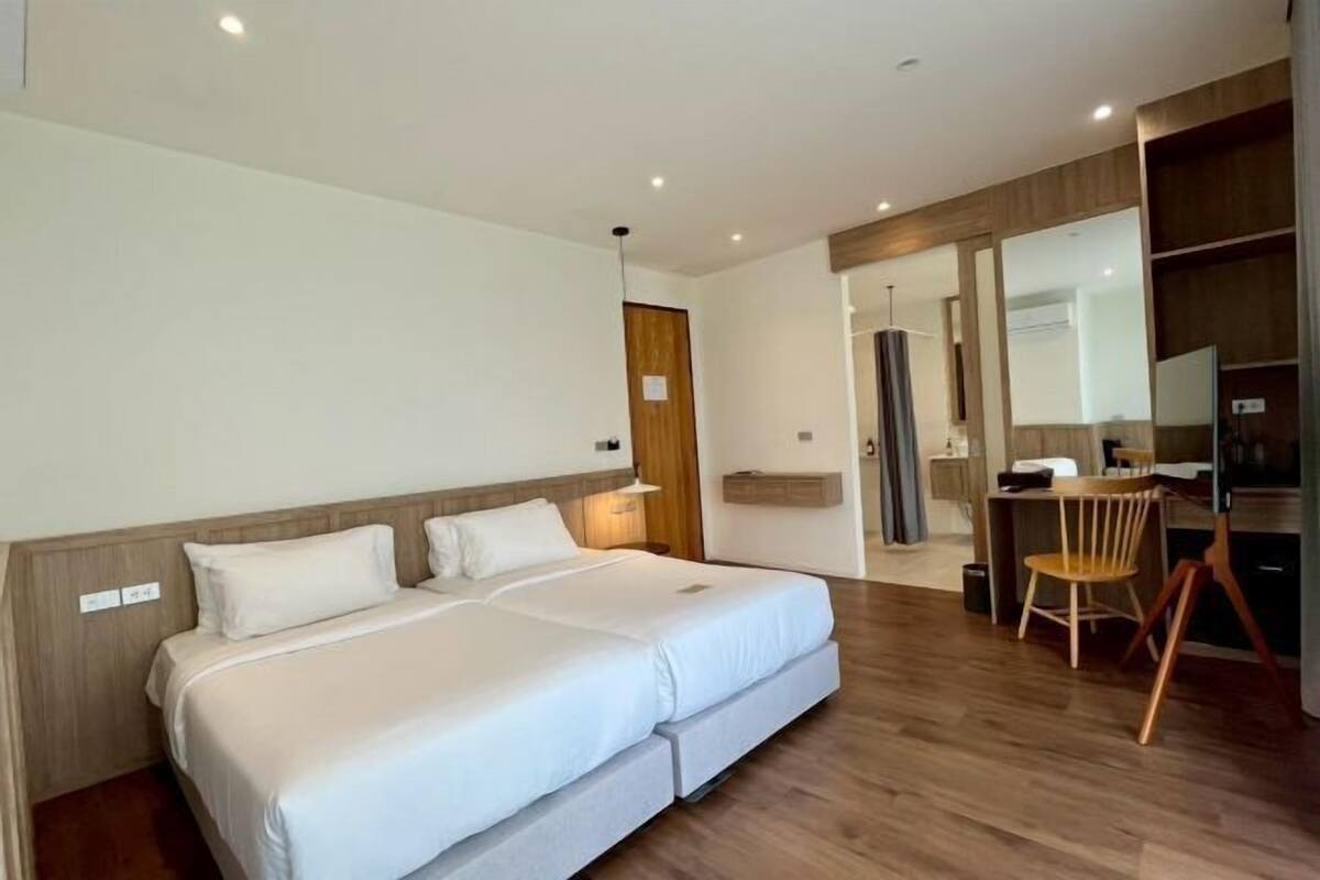 A modern hotel room with a double bed, a desk, a chair, and a large mirror.