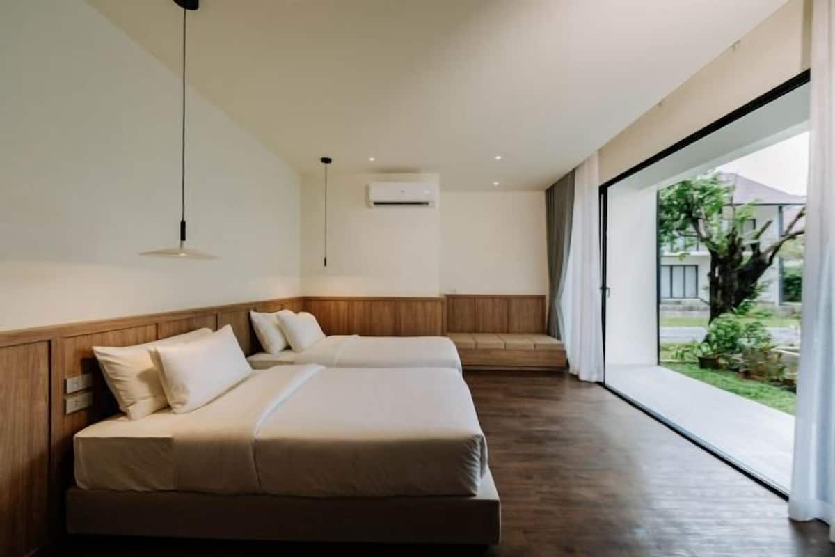 A modern hotel room with a large bed, a small desk, and a view of the outdoors.